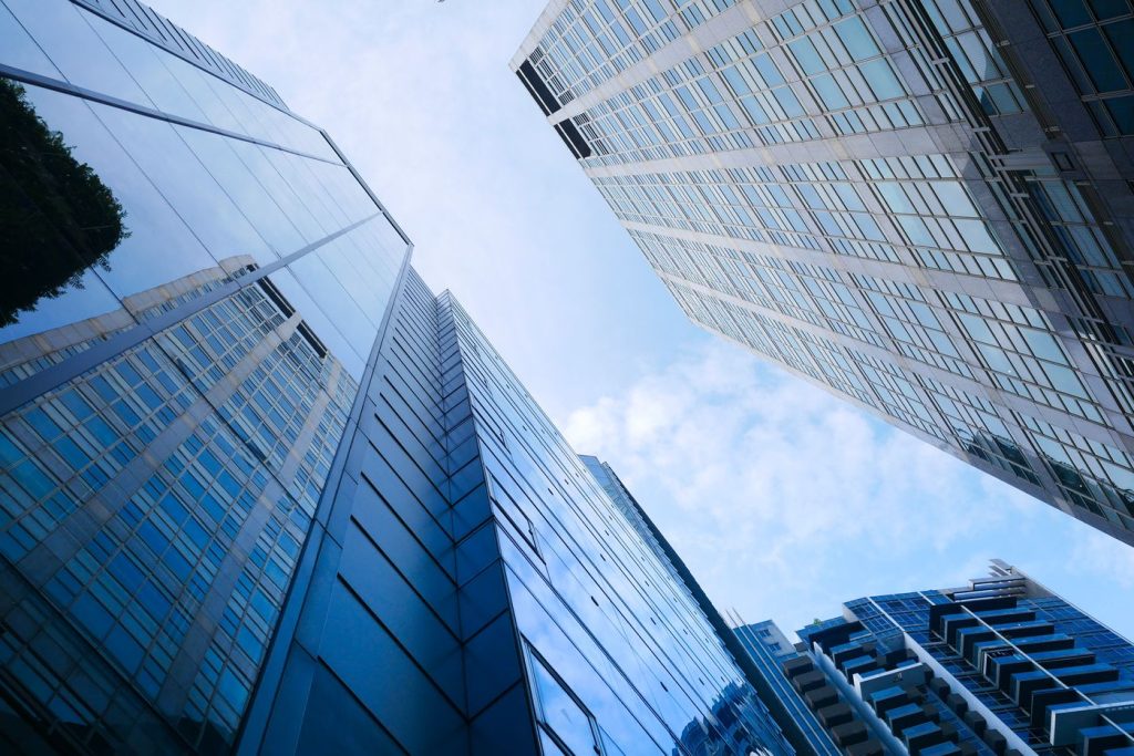 Glass corporate towers rising into a blue sky